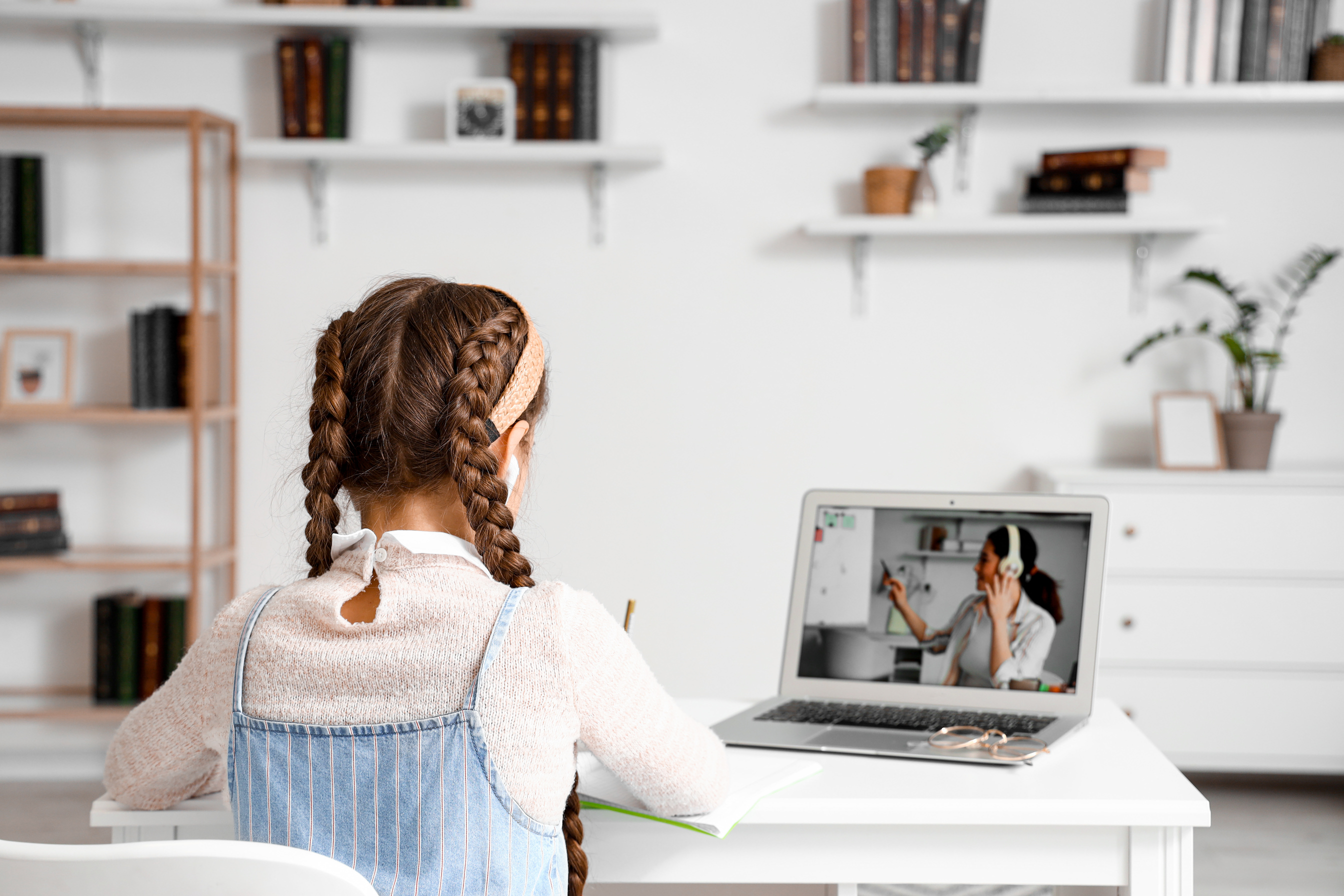 Little Girl in Earphones Studying with Online Tutor at Home, Back View